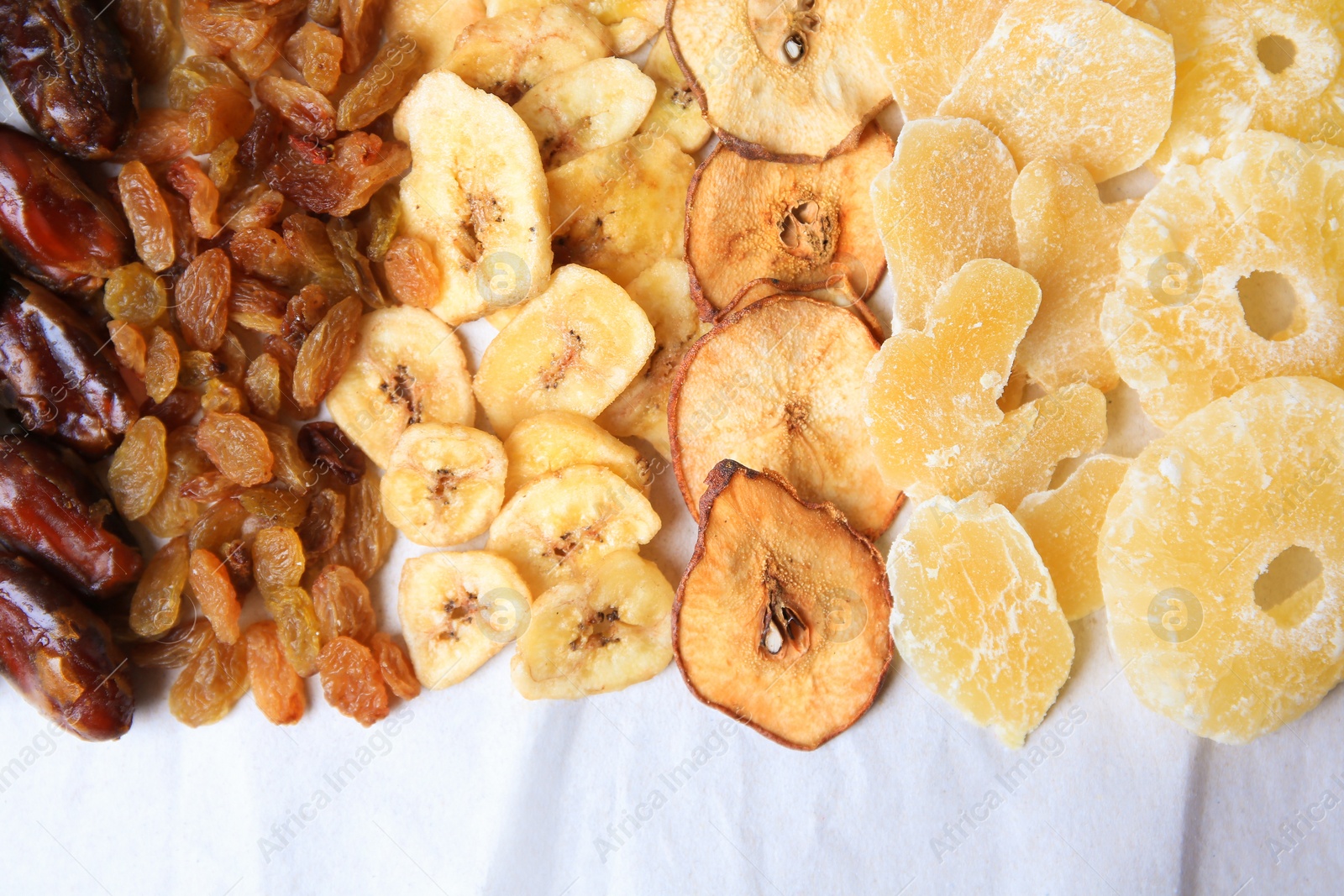 Photo of Different tasty dried fruits on paper, flat lay