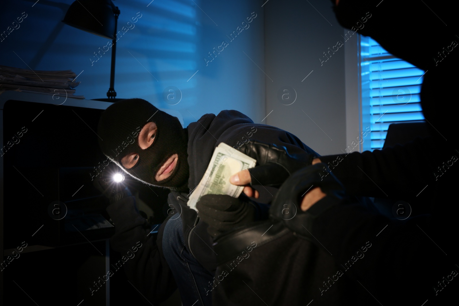 Photo of Thieves taking money out of steel safe indoors at night