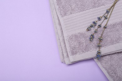 Terry towel and lavender flowers on violet background, top view. Space for text