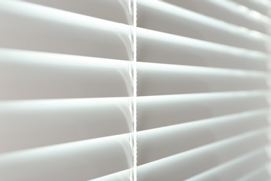 Photo of Closed modern white window blinds, closeup view