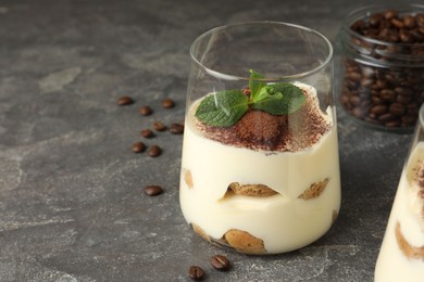 Delicious tiramisu with mint in glass on grey table. Space for text