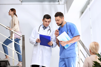 Doctors discussing patient's diagnosis on stairs in hospital