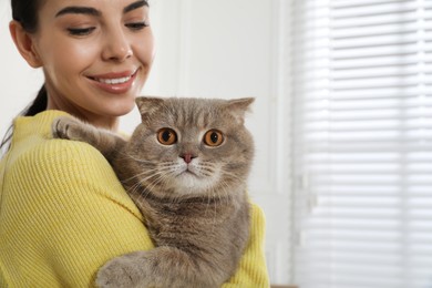 Woman with her adorable cat at home, space for text