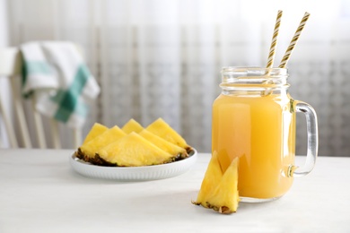 Photo of Delicious pineapple juice and fresh fruit on white table indoors. Space for text