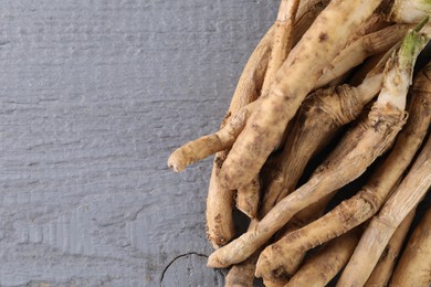 Photo of Fresh raw horseradish roots on grey wooden table, top view. Space for text