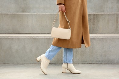 Stylish woman with trendy beige bag on stairs outdoors, closeup