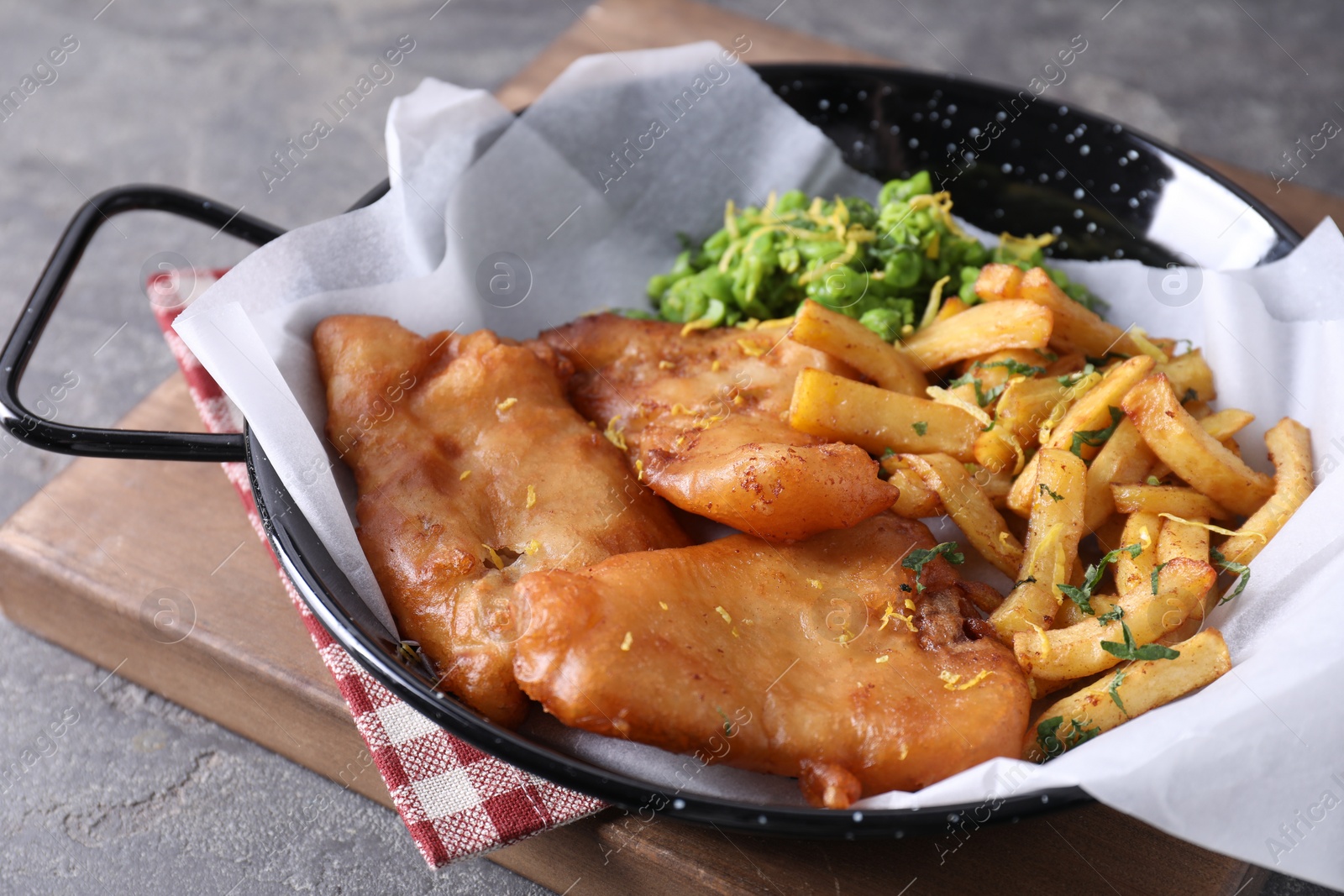 Photo of Tasty fish, chips and peas on grey table, closeup