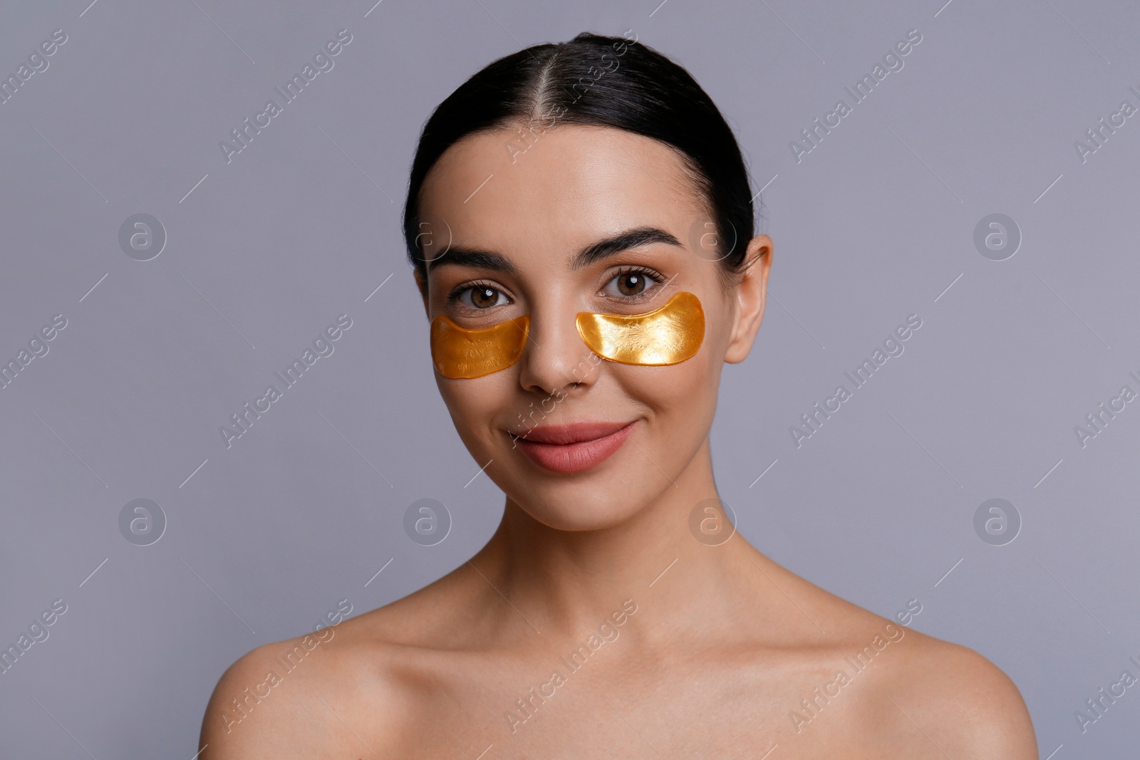 Photo of Beautiful young woman with under eye patches on grey background