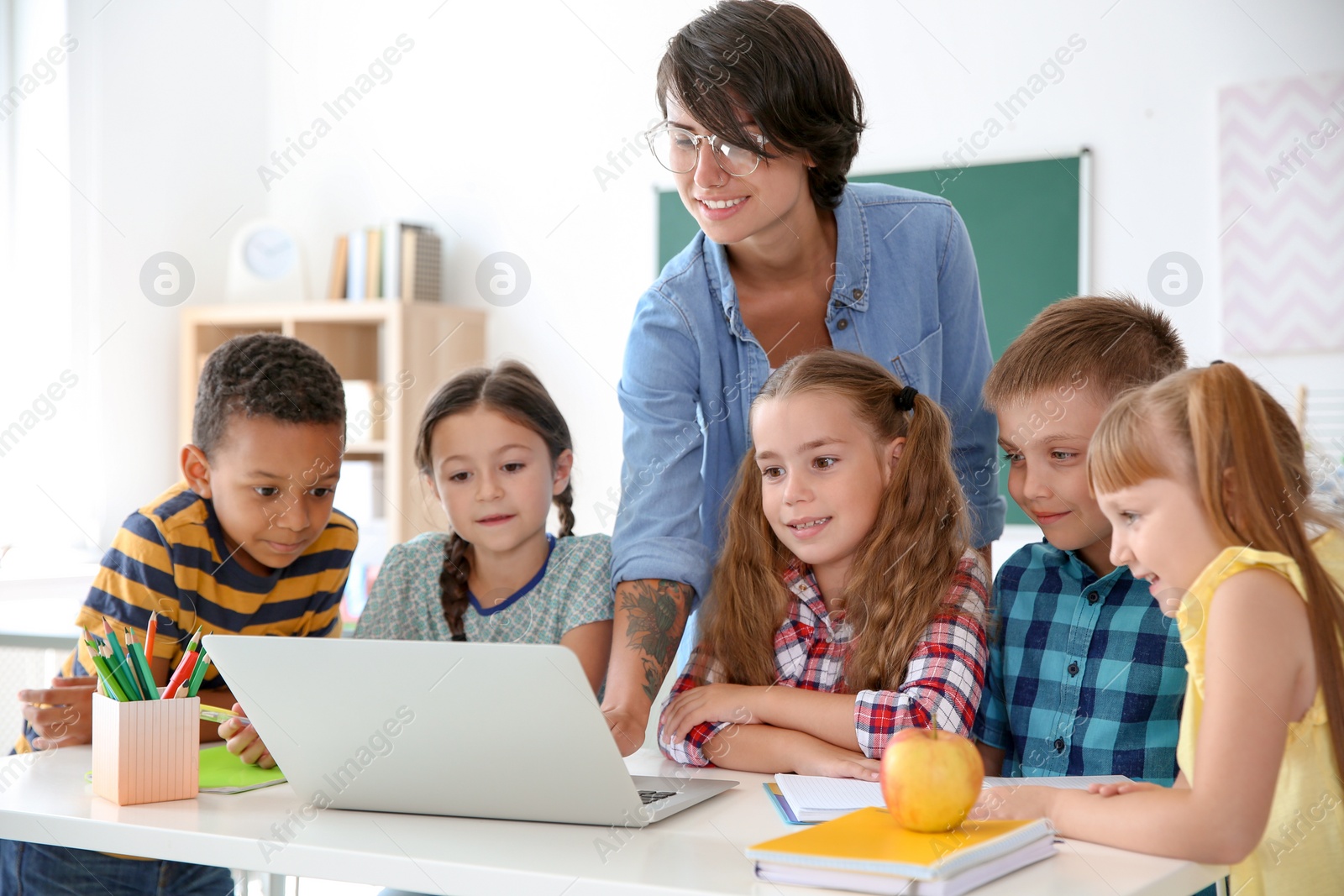 Photo of Female teacher helping children with assignment at school