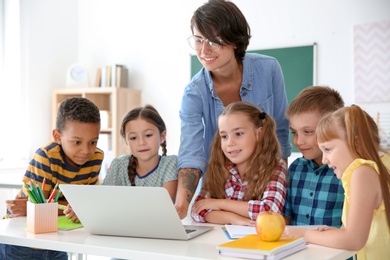 Female teacher helping children with assignment at school