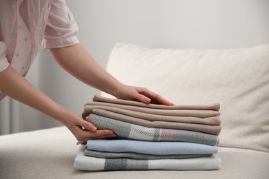 Photo of Woman with folded cashmere clothes indoors, closeup