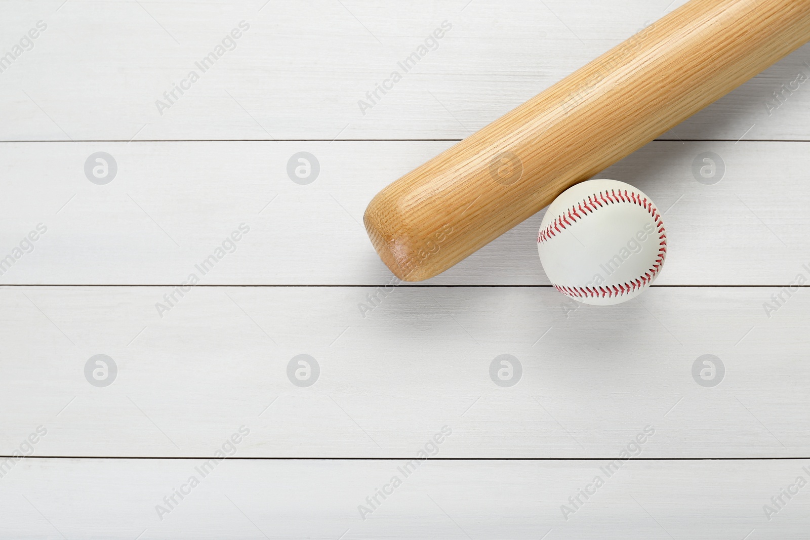 Photo of Baseball bat and ball on white wooden table, top view with space for text. Sports equipment