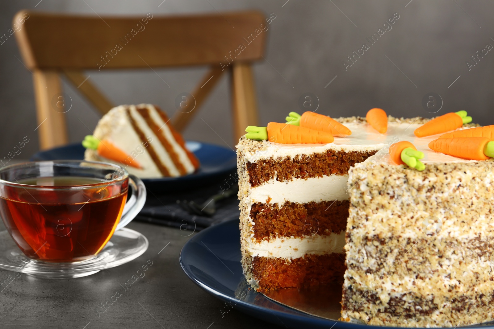 Photo of Tasty carrot cake and cup of fresh tea on grey table