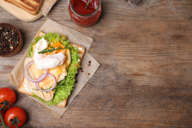 Photo of Tasty sandwich with chicken and poached egg on wooden table, flat lay. Space for text