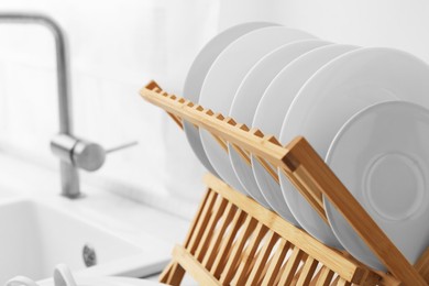 Photo of Drying rack with clean dishes in kitchen, closeup