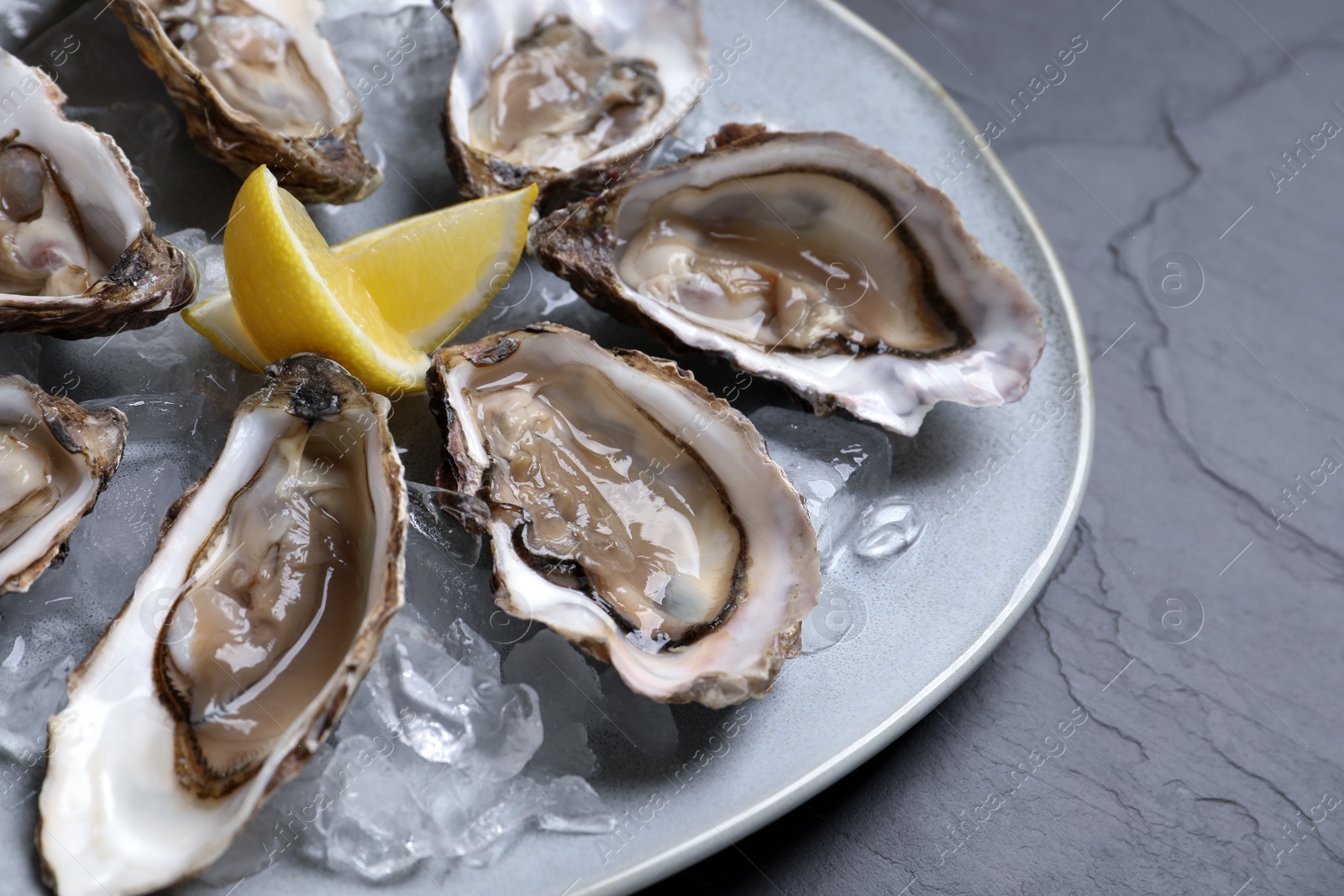 Photo of Delicious fresh oysters with lemon slices served on table, closeup