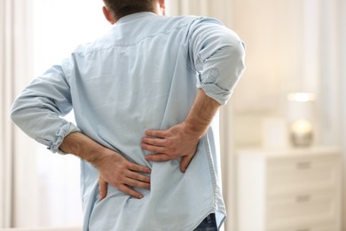 Photo of Man suffering from back pain at home, closeup. Bad posture problem