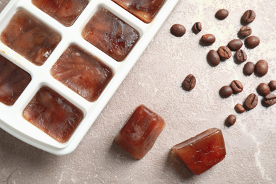 Ice cubes and coffee beans on grey table, flat lay