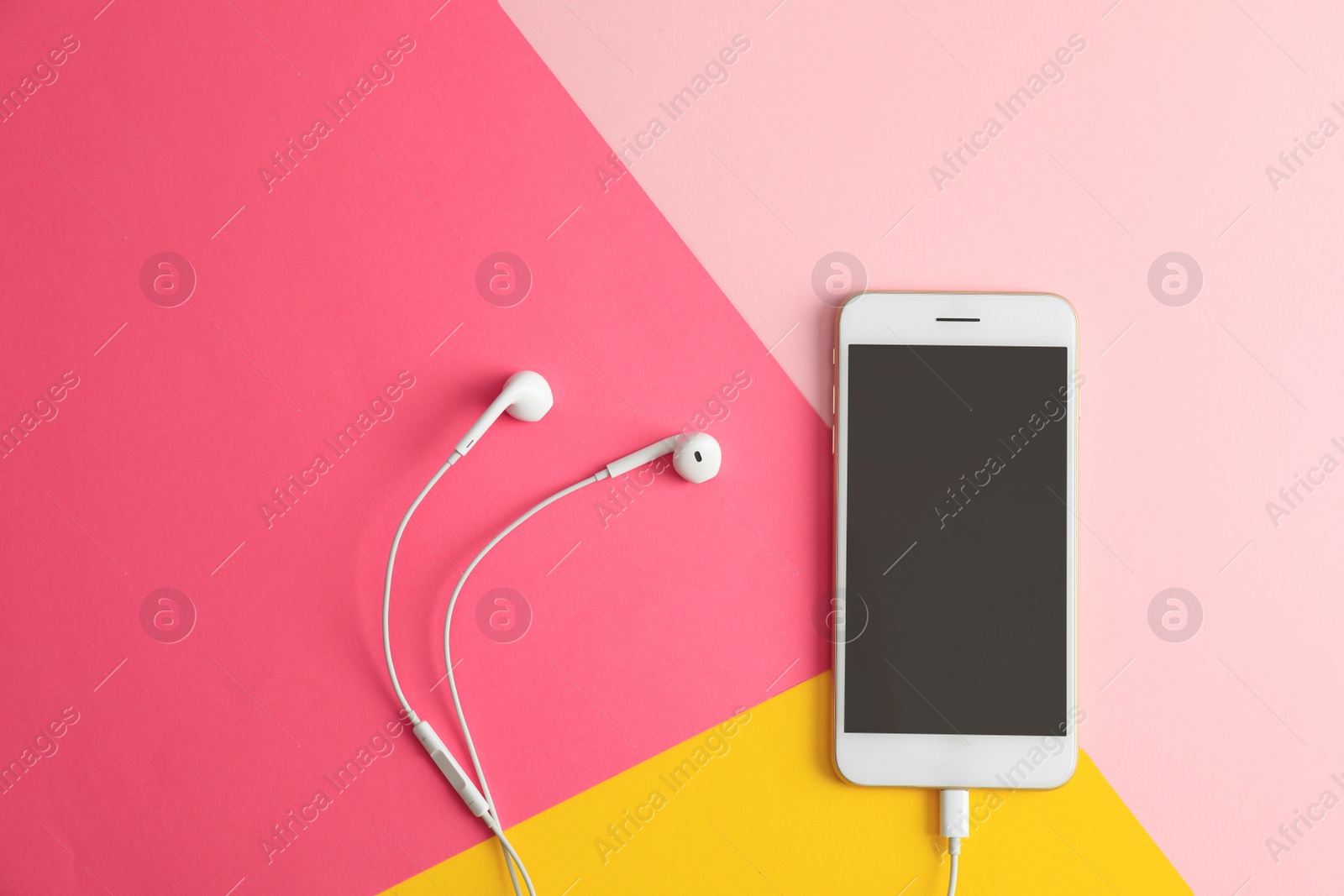 Photo of Modern phone with earphones on color background, top view. Space for text