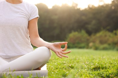 Woman practicing yoga on mat outdoors, closeup and space for text. Lotus pose