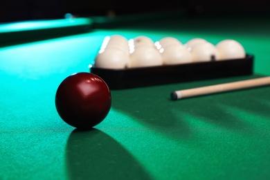 Photo of Billiard balls, triangle rack and cue on table. Space for text