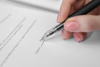 Woman signing documents with black pen, closeup