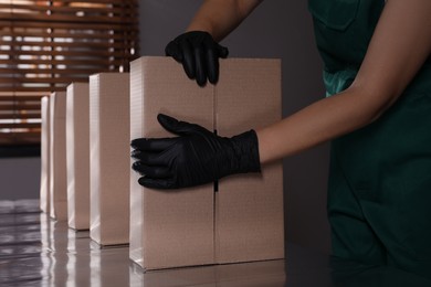 Photo of Woman packing cardboard boxes at production line indoors, closeup