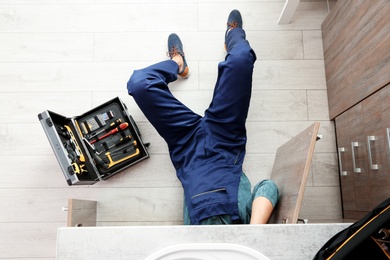 Male plumber repairing kitchen sink, top view