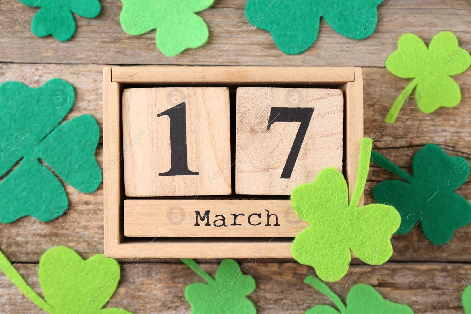 Photo of St. Patrick's day - 17th of March. Block calendar and felt clover leaves on wooden background, flat lay