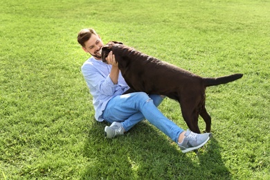 Photo of Cute brown labrador retriever with owner outdoors