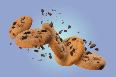 Image of Tasty chocolate chip cookies falling on light blue background