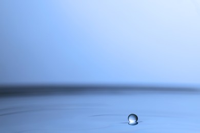 Photo of Drop falling into clear water on light grey background, closeup