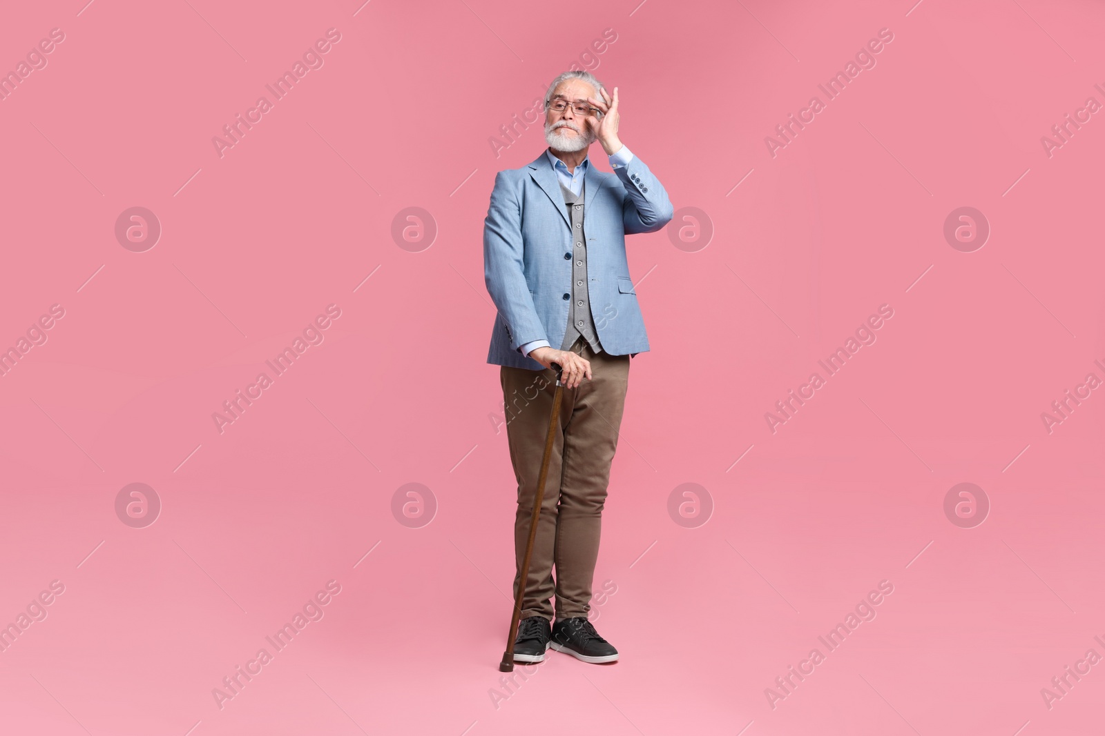 Photo of Senior man with walking cane on pink background