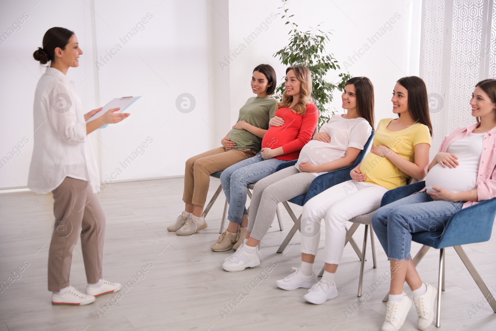 Photo of Group of pregnant women with midwife at courses for expectant mothers indoors