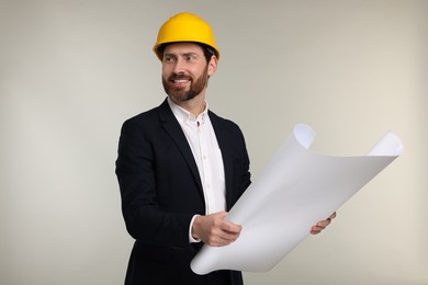 Photo of Architect in hard hat with draft on gray background