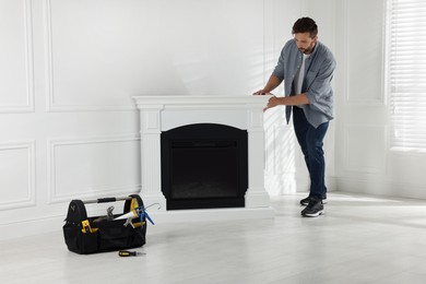 Photo of Man installing electric fireplace near white wall in room