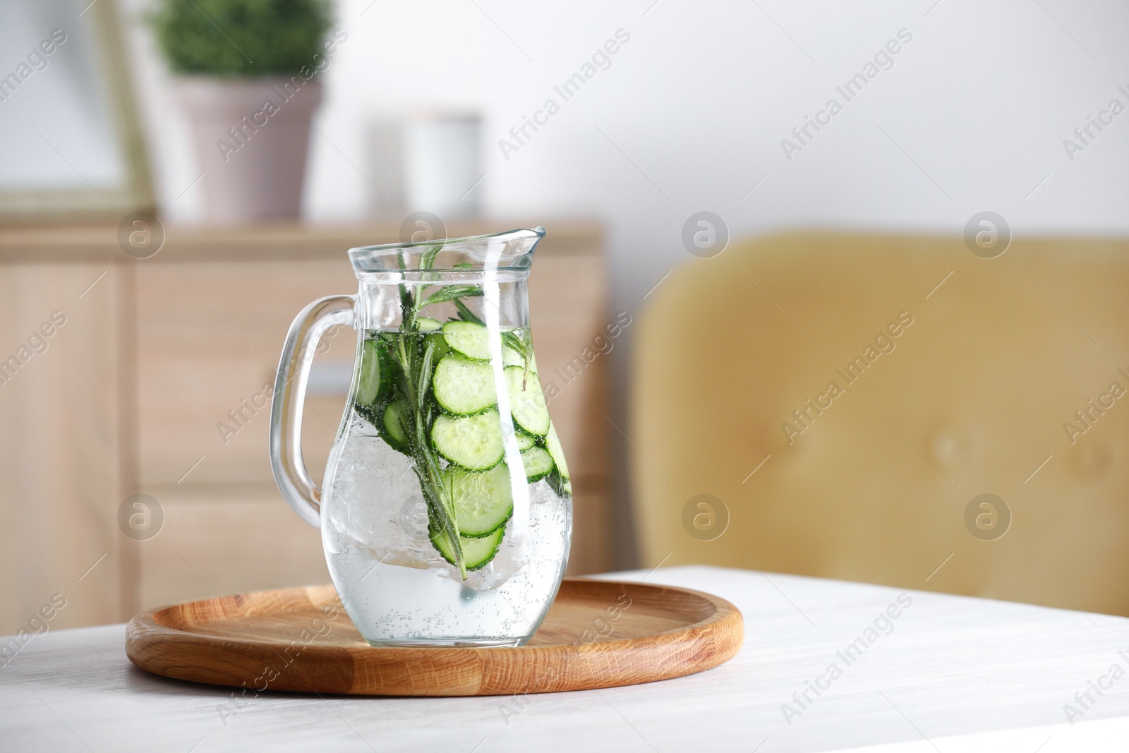 Photo of Refreshing cucumber water with rosemary in jug on white table. Space for text