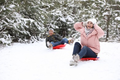 Photo of Happy couple sledding outdoors on winter day. Christmas vacation
