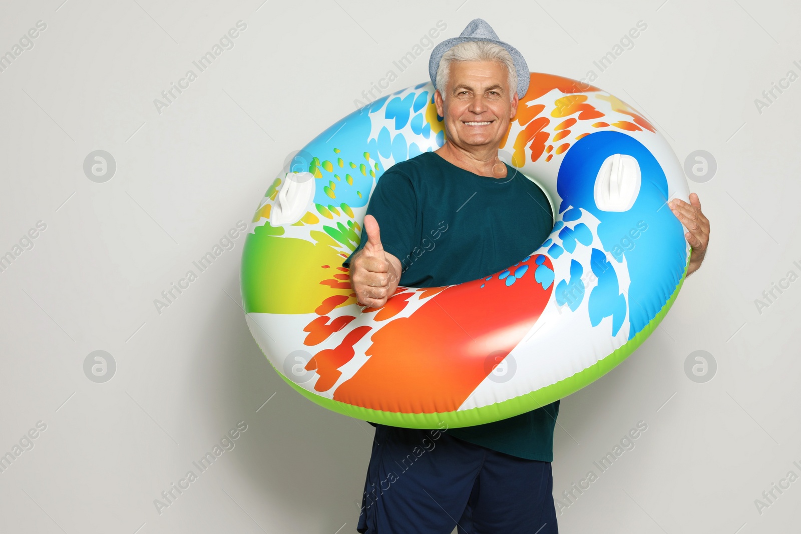 Photo of Funny mature man with bright inflatable ring on light background