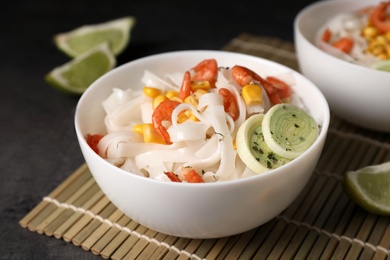 Photo of Bowl with rice noodles, shrimps and vegetables on table