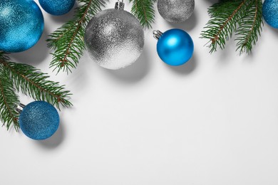Christmas balls and fir tree branches on white background, flat lay. Space for text
