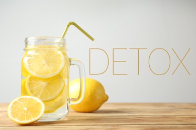 Image of Mason jar of lemon water on wooden table and word Detox