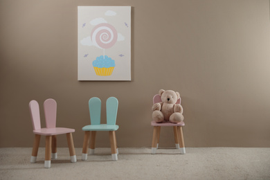 Photo of Cute chairs with bunny ears in children's room interior