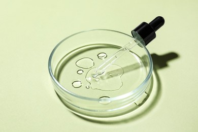 Photo of Petri dish with pipette and sample on light green background