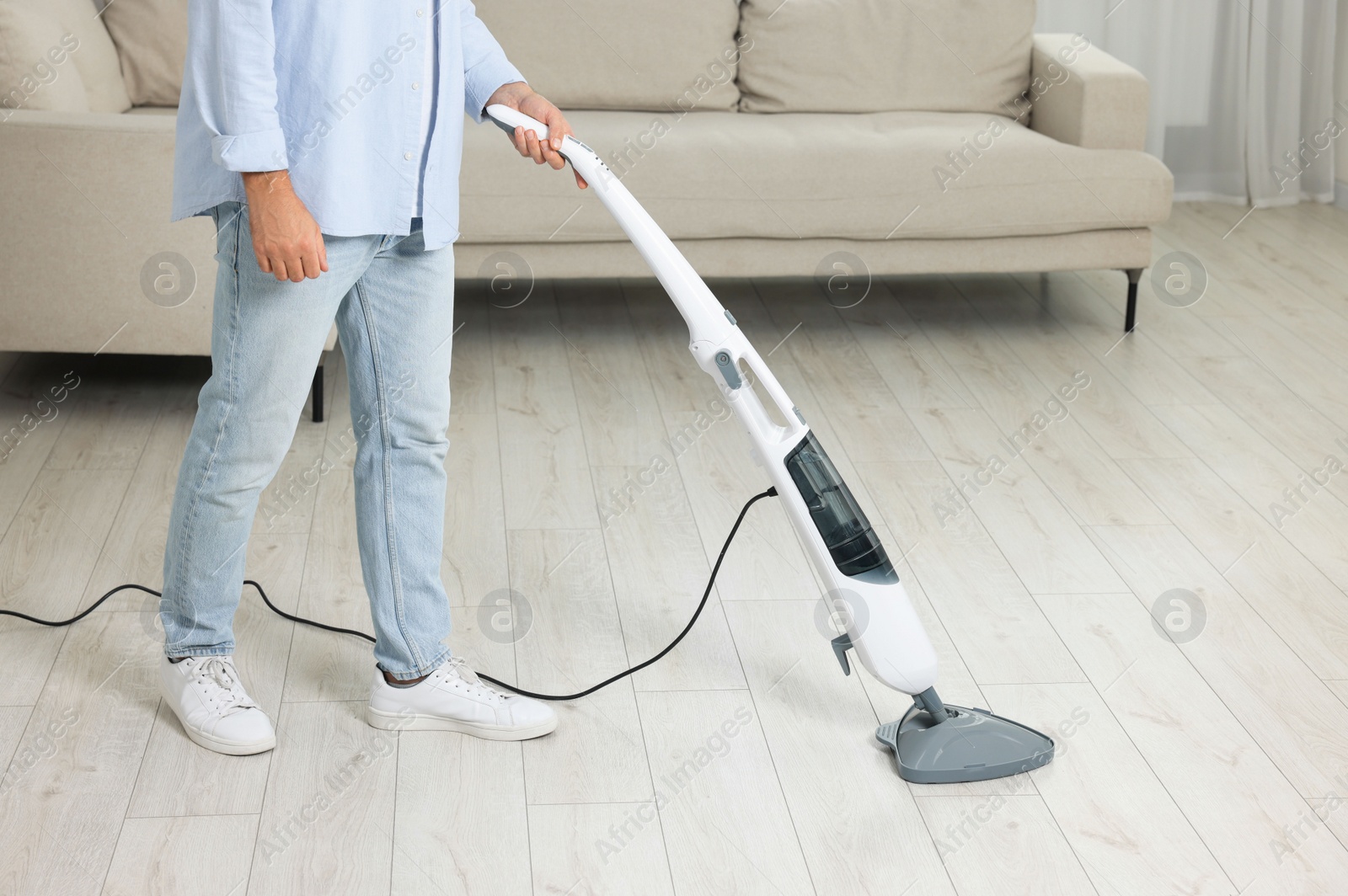 Photo of Man cleaning floor with steam mop at home, closeup