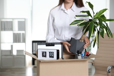 Young woman packing stuff in box at office, closeup