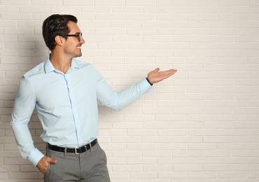 Young male teacher with glasses near brick wall. Space for text