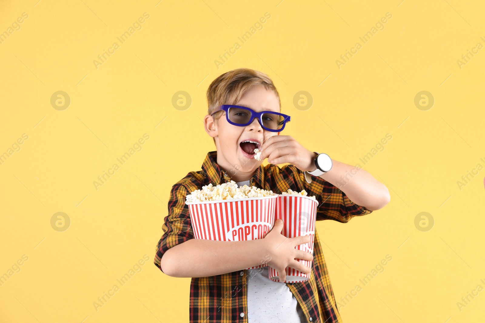 Photo of Cute boy in 3D glasses with popcorn buckets on color background