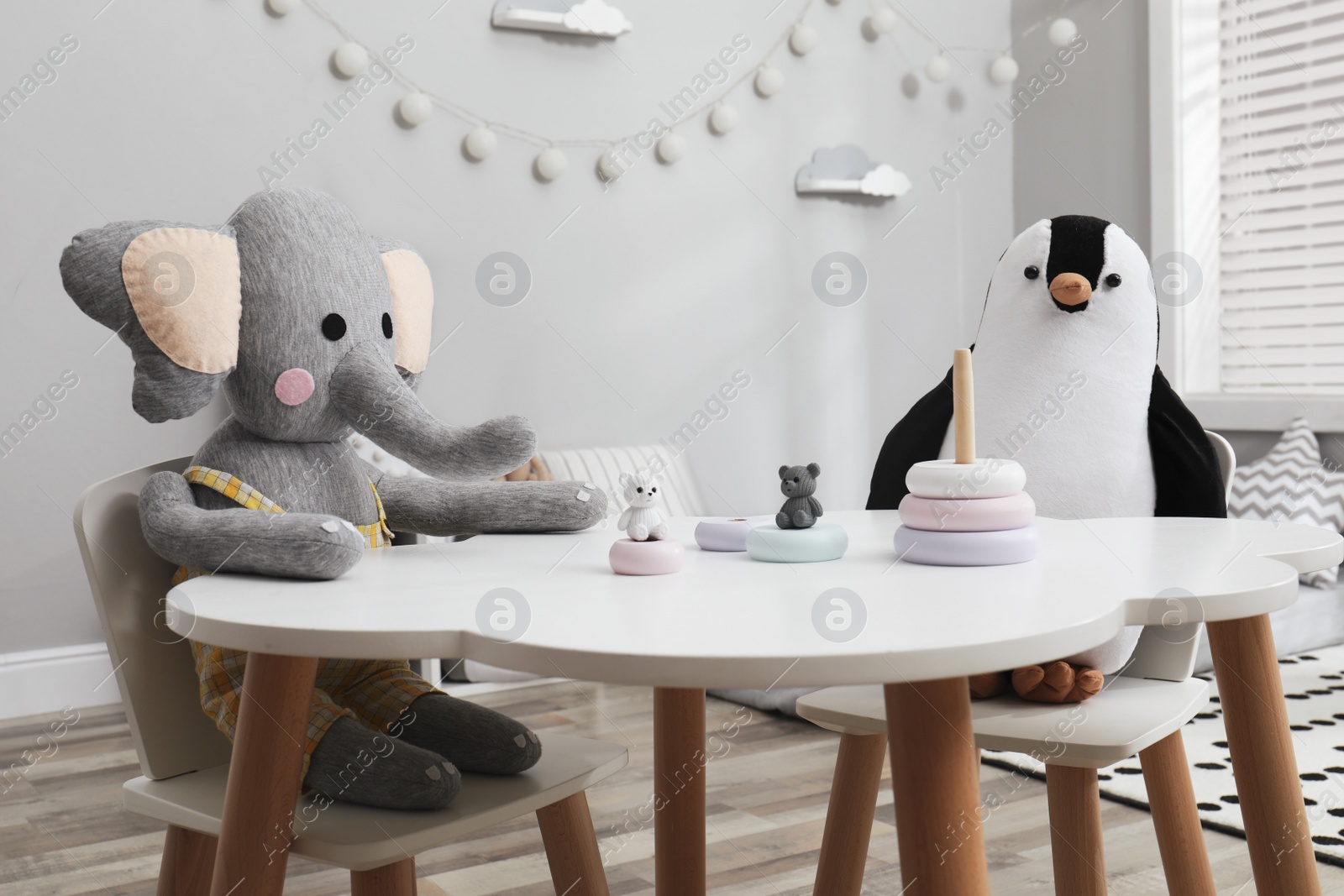 Photo of Cute toys at white table in child's room. Interior design