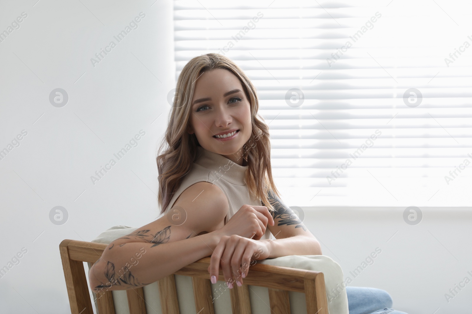 Photo of Beautiful woman with tattoos on arms resting at home